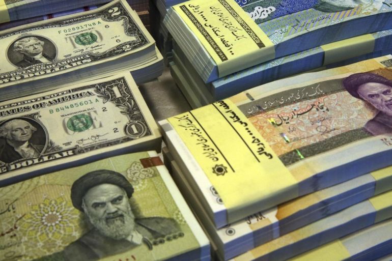 FILE--In this Saturday, April 4, 2015 file photo, Iranian and U.S. banknotes are on display at a currency exchange shop in downtown Tehran, Iran. Iran said Tuesday, Jan. 19, 2016,  it successfully transferred some of the billions of dollars' worth of frozen overseas assets following the implementation of the nuclear deal with world powers. But ordinary Iranians are still waiting to see how their daily lives will improve and how fast Iranian companies will gain access to financial markets worldwide. (AP Photo/Vahid Salemi,File)